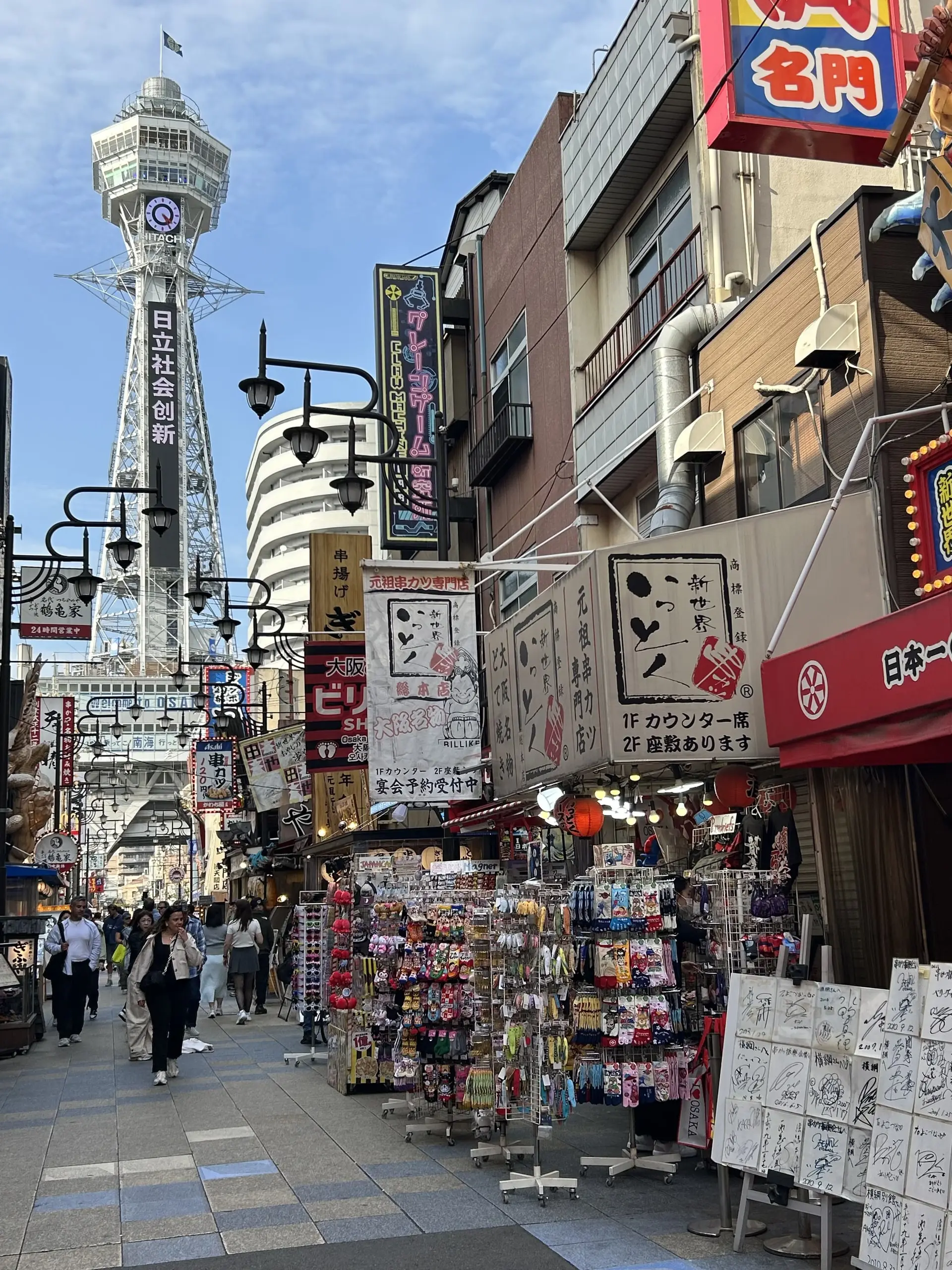 Ocelová věž Cútenkaku se tyčí nad ulicí Šinsekai plnou japonských nápisů a stojanů se suvenýry.