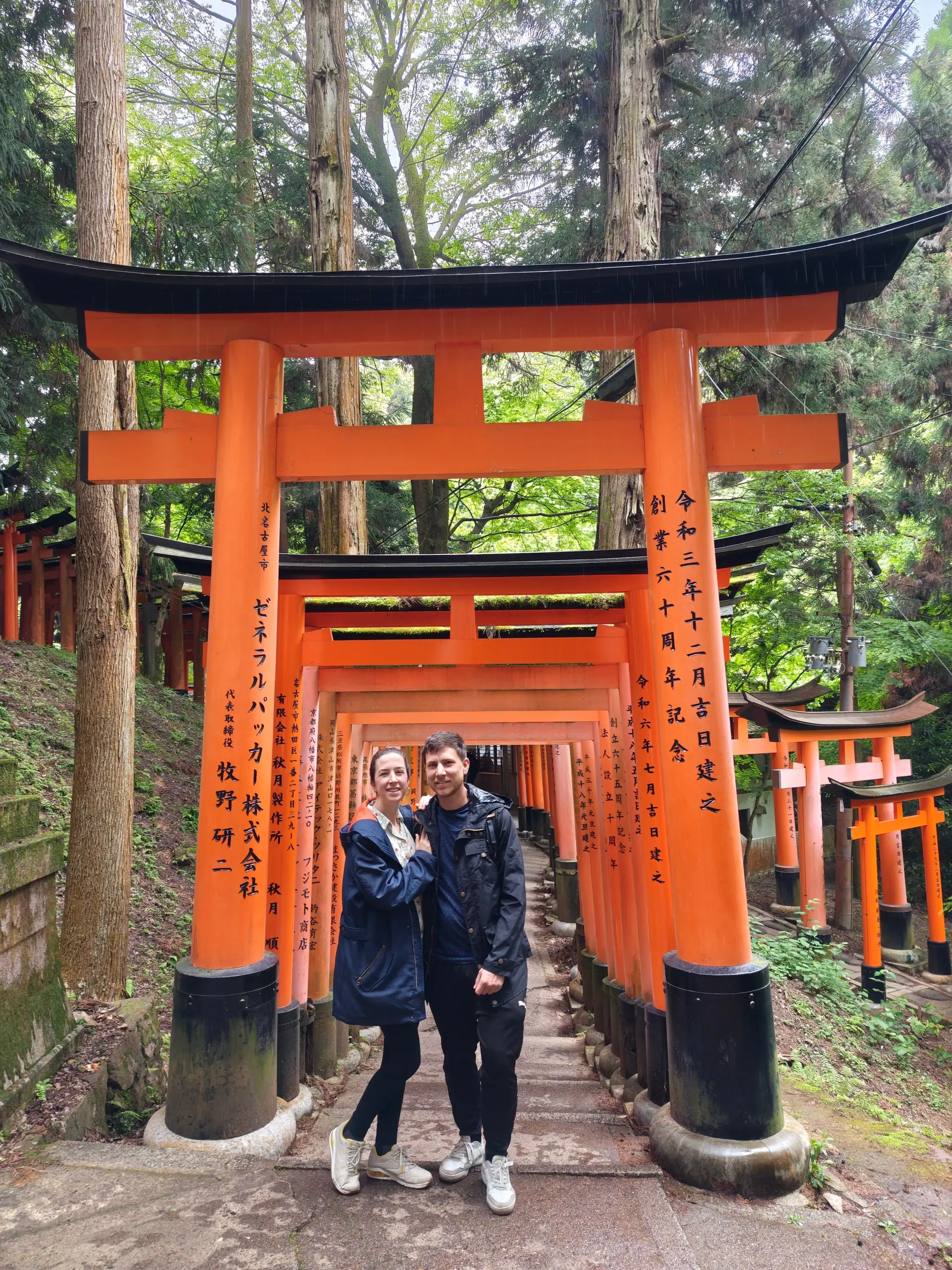 Pěšina vede tunelem oranžových torií popsaných černými japonskými znaky.