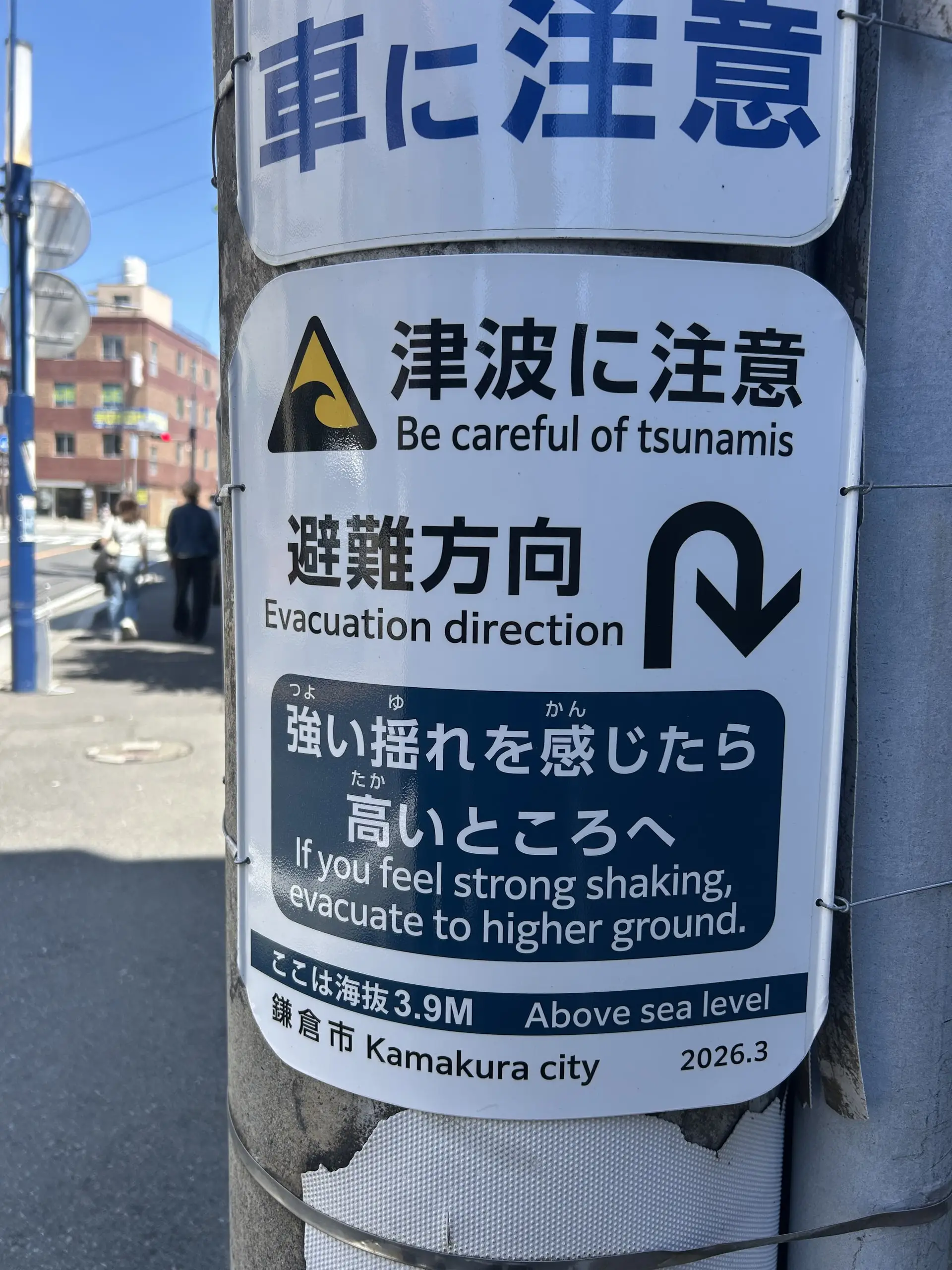 Cedule na sloupu varuje před tsunami a ukazuje směr evakuace ve městě Kamakura.