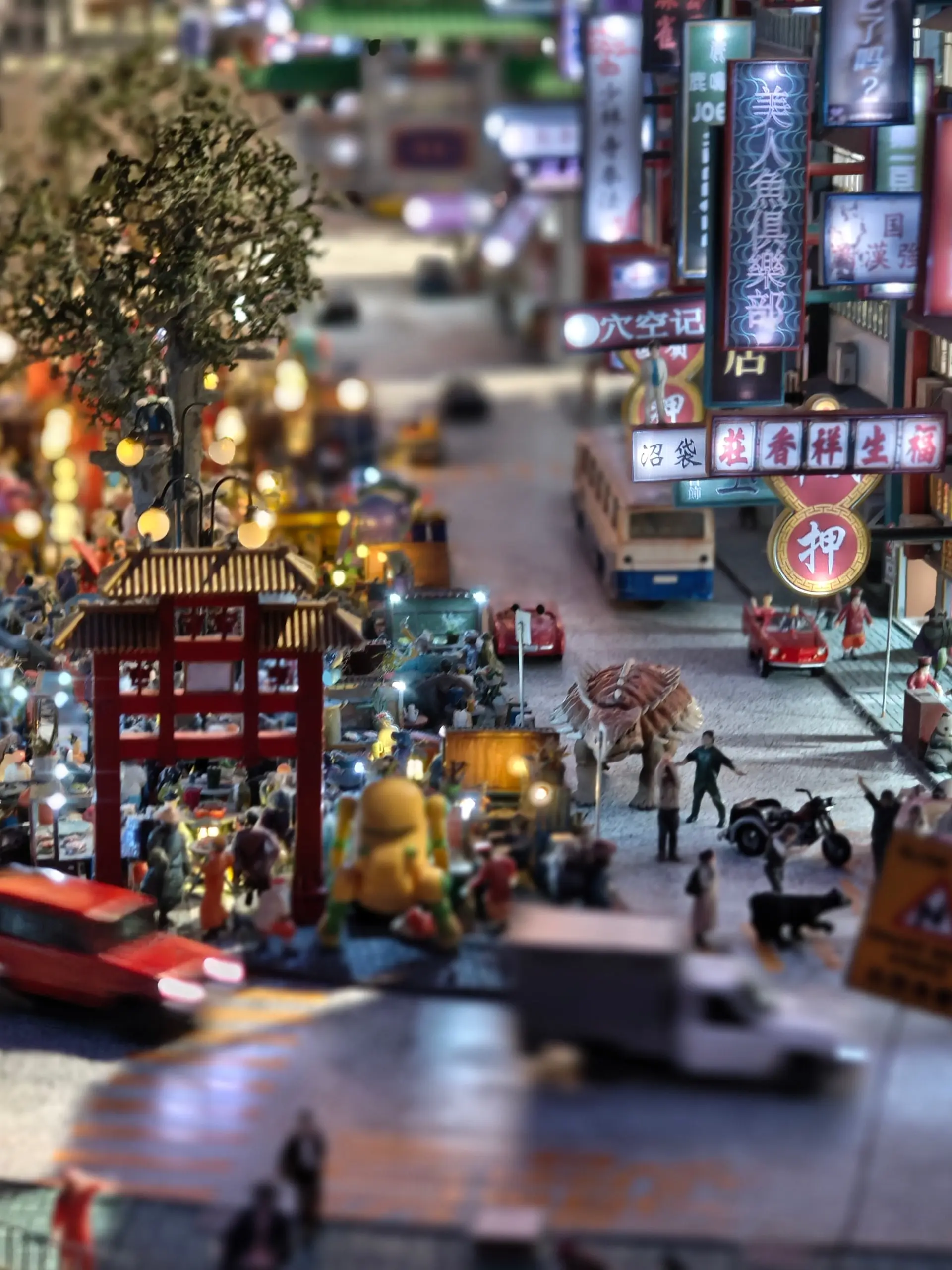 Miniaturní model rušné noční asijské ulice s neonovými poutači na výstavě Small Worlds.