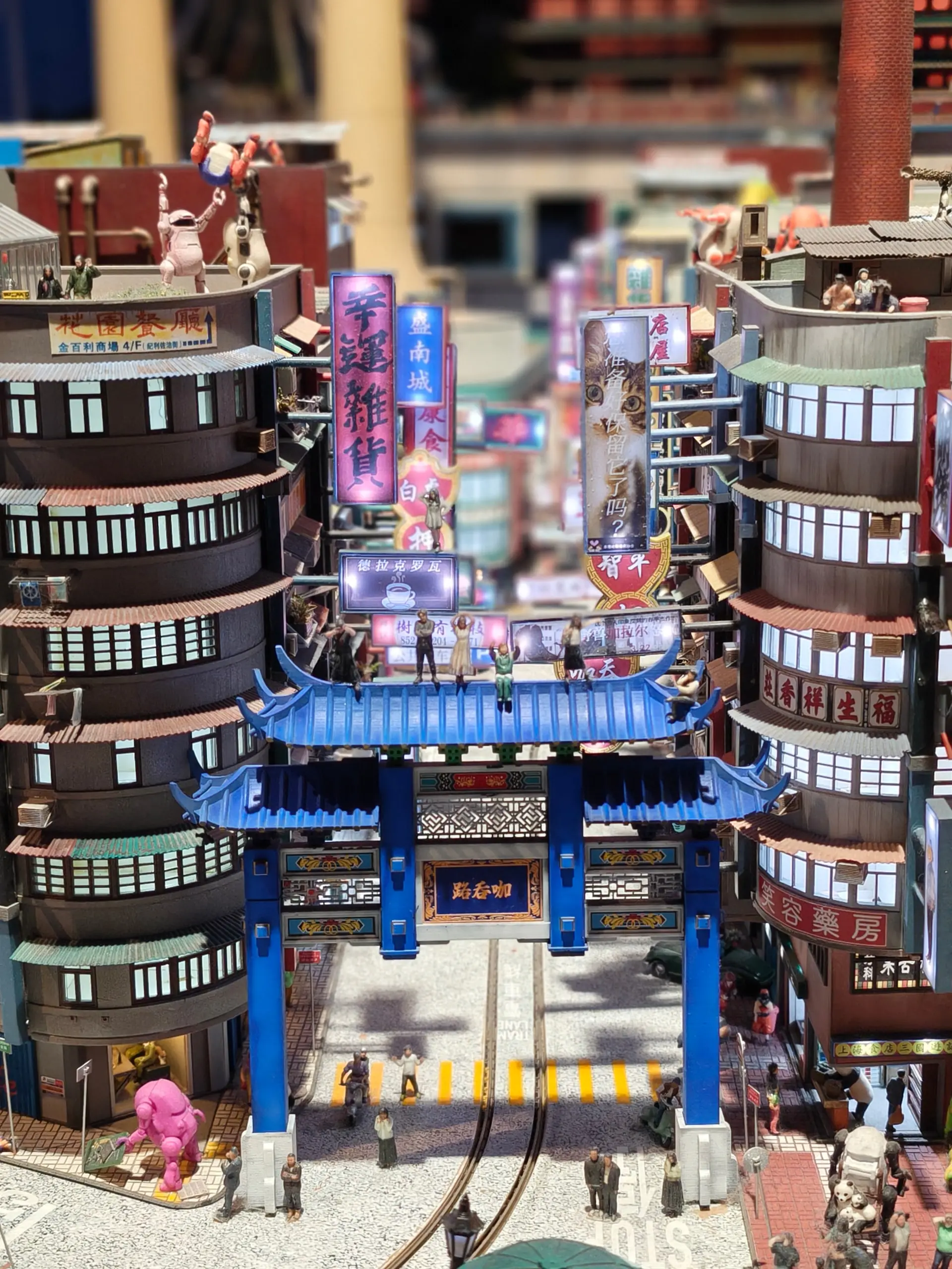 Miniaturní model modré asijské brány mezi okrouhlými mrakodrapy na výstavě Small Worlds.