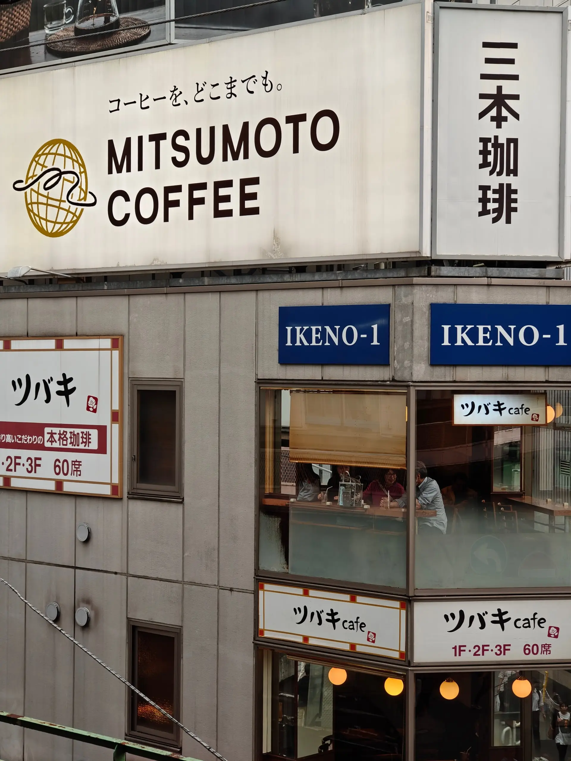 Fasáda kavárny Mitsumoto Coffee s velkými cedulemi a prosklenou kavárnou Tsubaki.