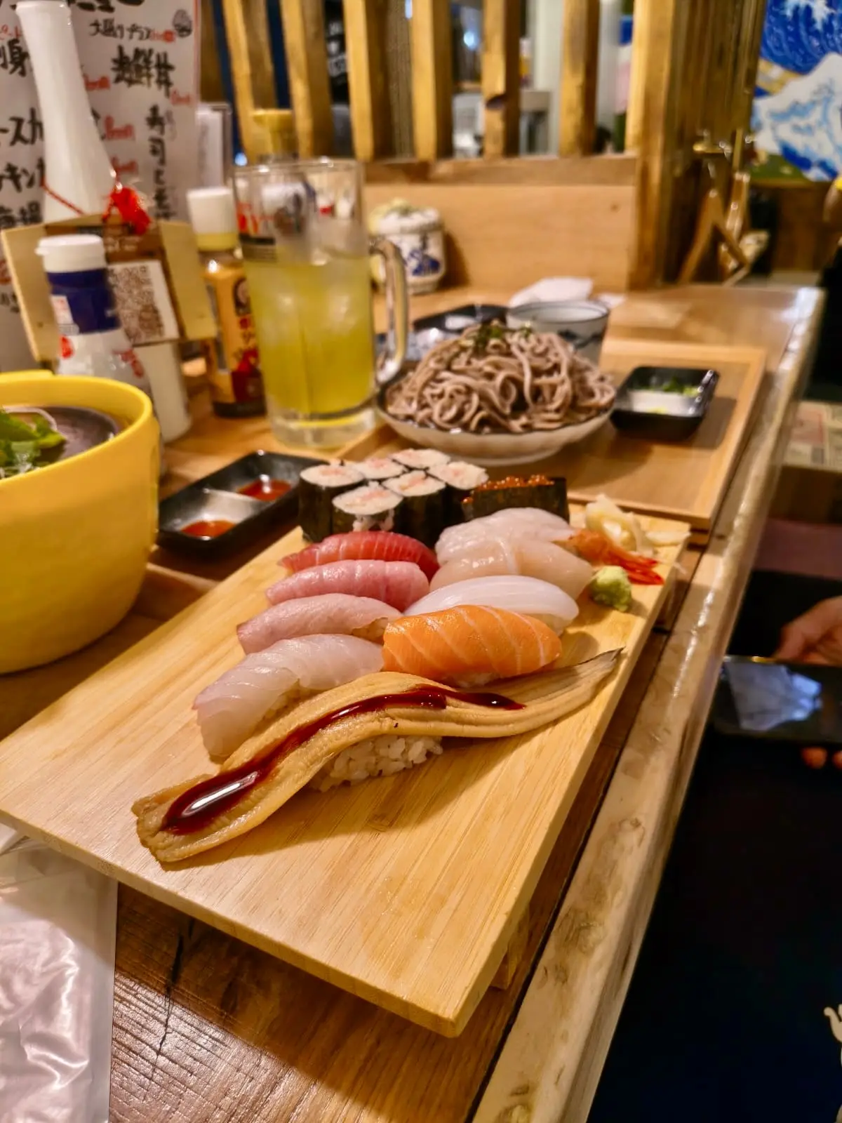 Dřevěná deska s nigiri sushi, závitky a miso polévkou na pultu restaurace.